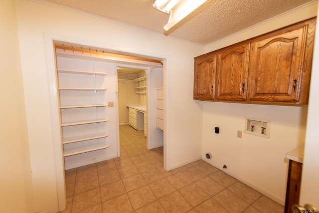 laundry room with cabinets, hookup for a washing machine, electric dryer hookup, crown molding, and light tile patterned floors