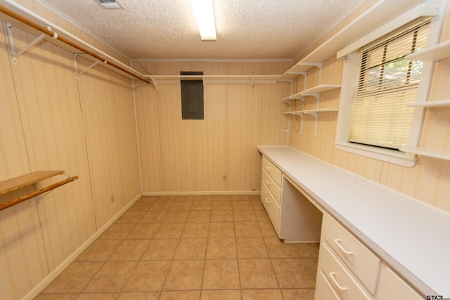 walk in closet featuring light tile patterned floors, built in desk, and electric panel