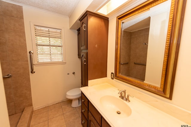 bathroom featuring vanity, tile patterned flooring, toilet, a textured ceiling, and a tile shower