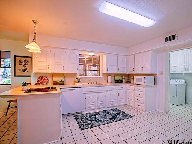 kitchen featuring washer / dryer, hanging light fixtures, sink, white cabinets, and white appliances