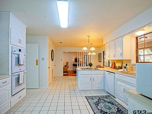 kitchen with kitchen peninsula, hanging light fixtures, white appliances, a notable chandelier, and white cabinets