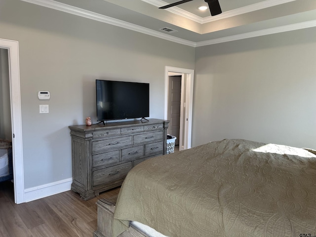 bedroom with visible vents, a raised ceiling, dark wood-style floors, crown molding, and baseboards