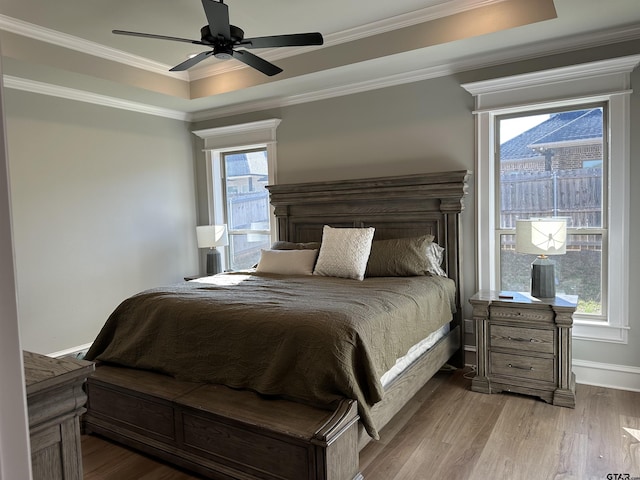 bedroom with ornamental molding, a raised ceiling, a ceiling fan, and wood finished floors