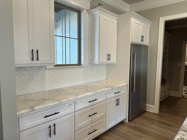 kitchen with ornamental molding, light stone counters, dark wood-style floors, high end fridge, and white cabinetry