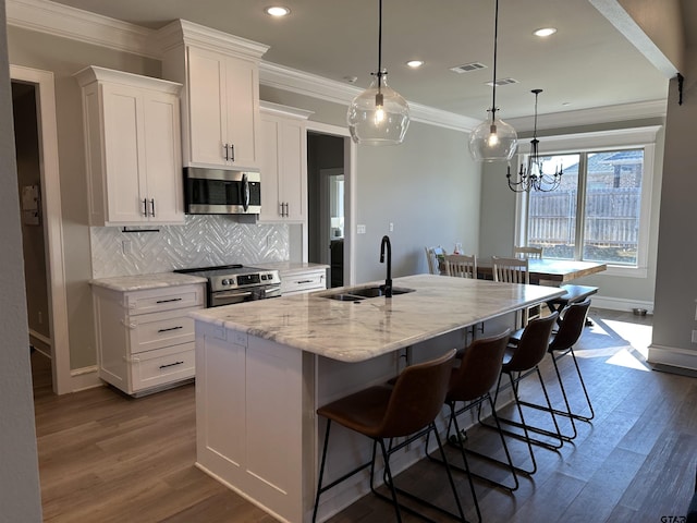 kitchen with visible vents, ornamental molding, a sink, appliances with stainless steel finishes, and white cabinets