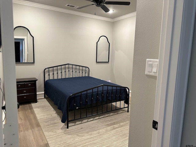 bedroom featuring ceiling fan, light wood-style flooring, visible vents, and ornamental molding