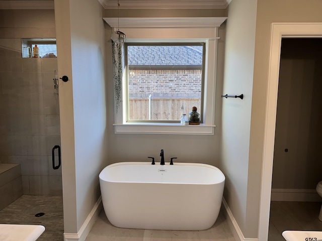 bathroom featuring a shower stall, toilet, a freestanding bath, and baseboards