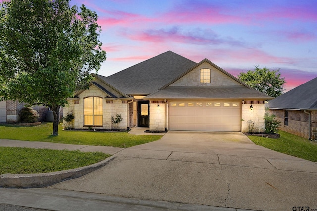 1625 Skidmore Ln, Tyler, TX 75703 - view of front of house featuring stone siding, driveway, a front lawn, an attached garage, and roof with shingles