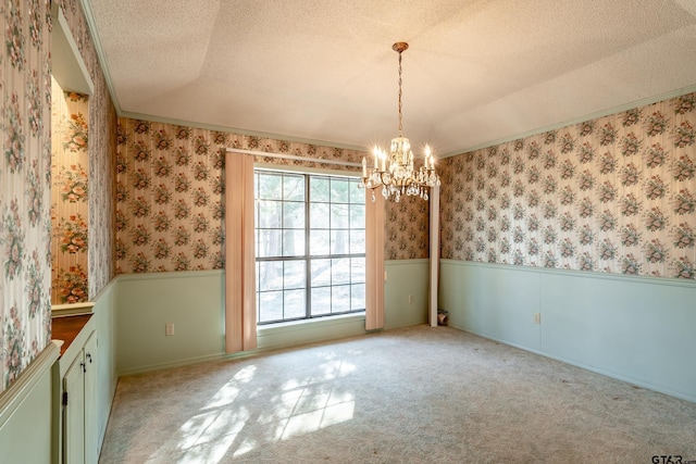 unfurnished dining area featuring light carpet, a chandelier, a textured ceiling, and ornamental molding