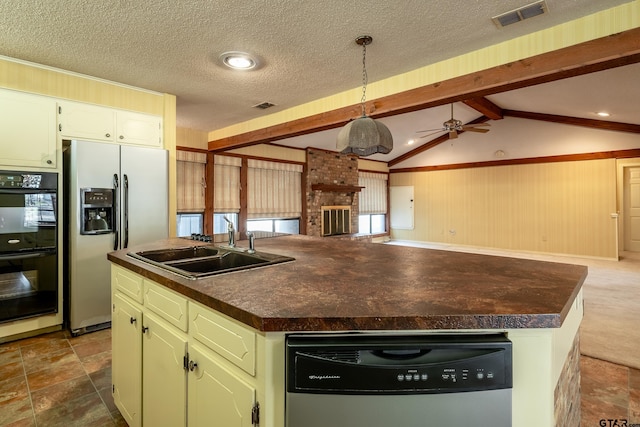 kitchen featuring a textured ceiling, stainless steel appliances, ceiling fan, decorative light fixtures, and a center island with sink