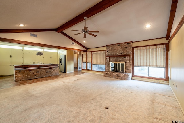 unfurnished living room with ceiling fan, lofted ceiling with beams, light colored carpet, and a fireplace