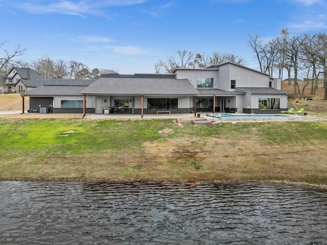 back of property featuring a water view, a patio, and a yard