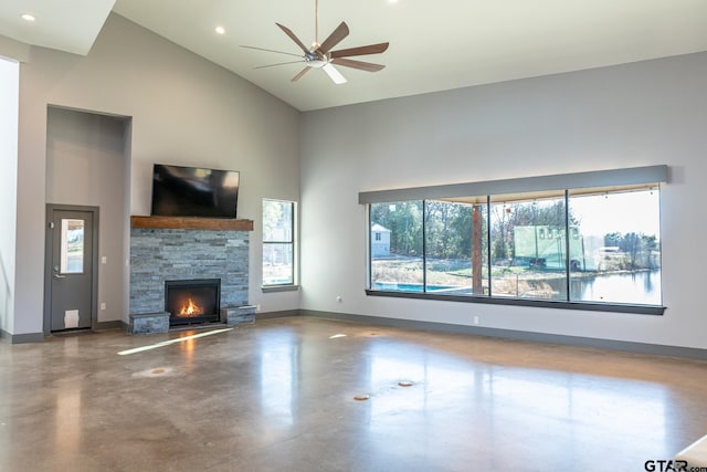 unfurnished living room with concrete flooring, a fireplace, ceiling fan, and high vaulted ceiling