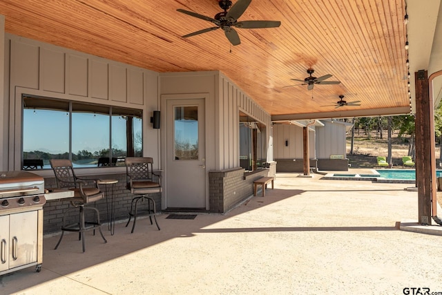 view of patio / terrace featuring exterior bar, a swimming pool with hot tub, ceiling fan, an outdoor kitchen, and a grill