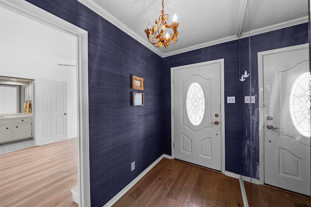 foyer entrance with hardwood / wood-style floors, a textured ceiling, ornamental molding, and a notable chandelier