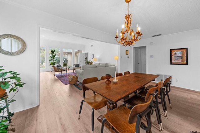 dining space with a notable chandelier, crown molding, and light hardwood / wood-style flooring