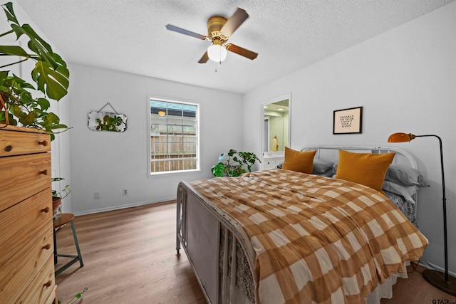 bedroom with a textured ceiling, light hardwood / wood-style floors, ensuite bath, and ceiling fan