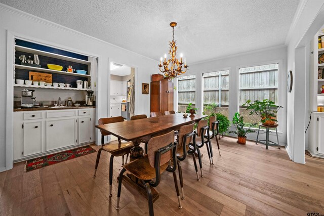 dining room with crown molding, a notable chandelier, a textured ceiling, and light wood-type flooring