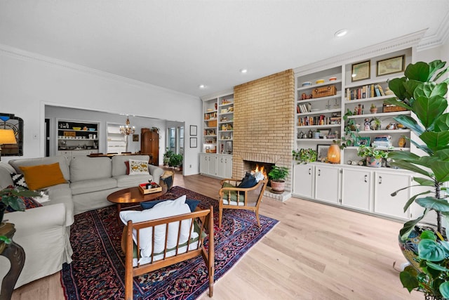 living room with a fireplace, built in shelves, light hardwood / wood-style flooring, and ornamental molding