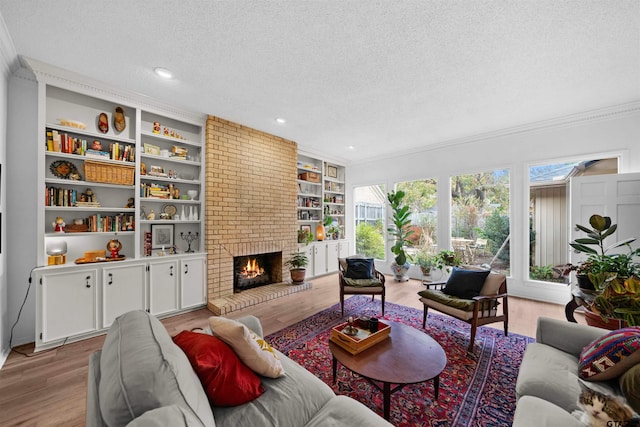 living room with a textured ceiling, crown molding, light wood-type flooring, and a fireplace