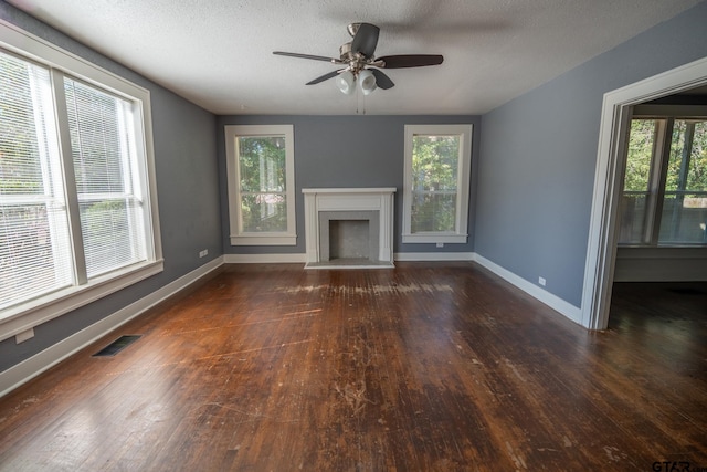 unfurnished living room featuring ceiling fan, a wealth of natural light, a textured ceiling, and dark hardwood / wood-style floors