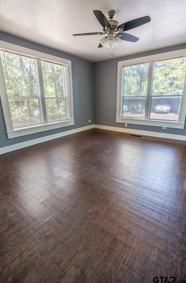 spare room featuring dark wood-type flooring, ceiling fan, and a textured ceiling