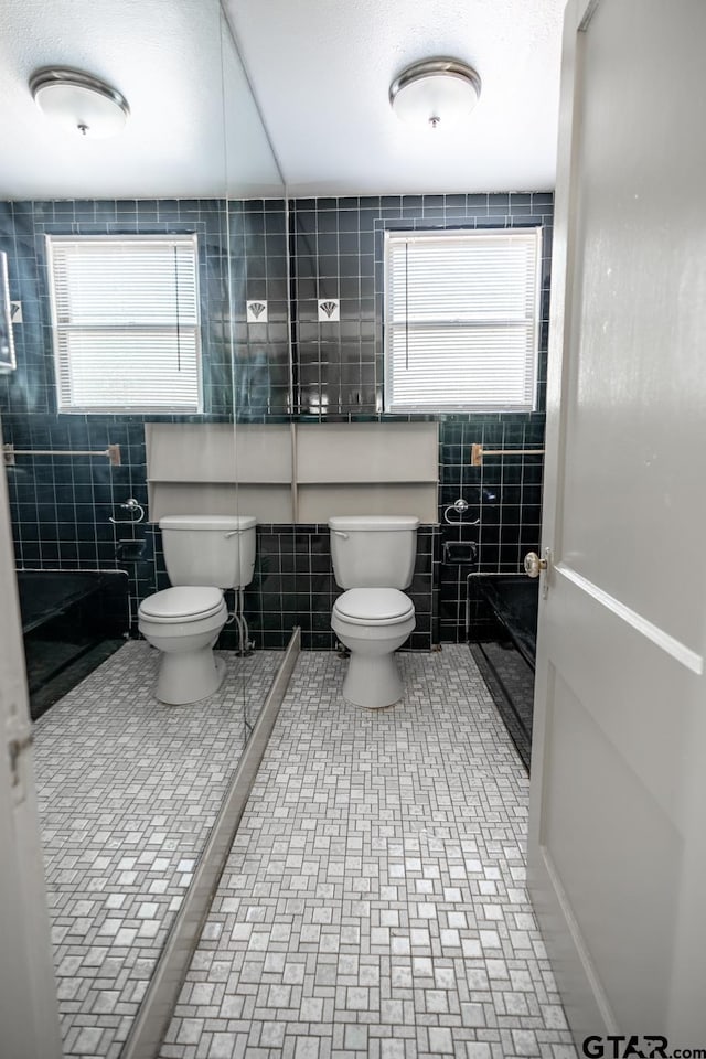 bathroom with toilet and tile walls