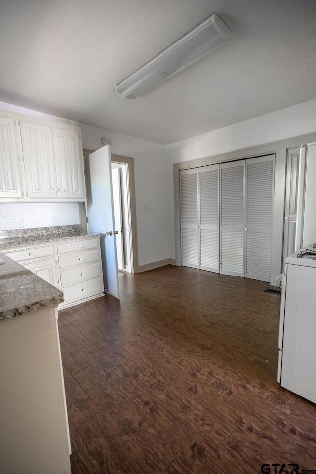 kitchen featuring white cabinets, light stone counters, dark hardwood / wood-style flooring, and white range oven