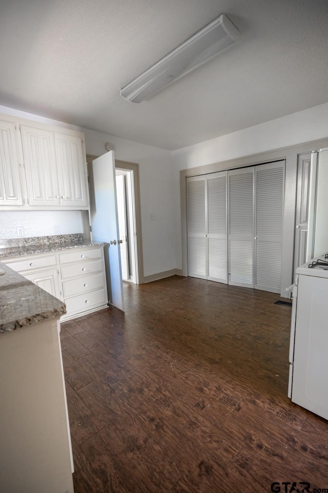 701 W Houston St, Tyler, TX 75702 - kitchen featuring stove, white cabinetry, dark wood-style floors, and light stone counters