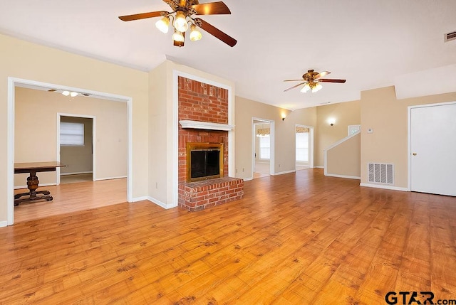 unfurnished living room with a brick fireplace, light hardwood / wood-style floors, and ceiling fan