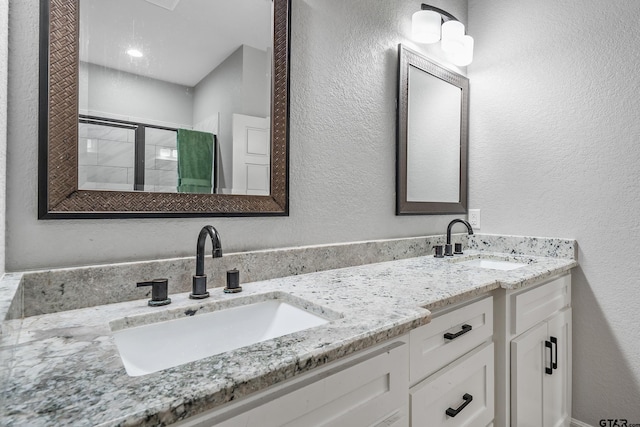 20851 Lakeview Dr, Flint, TX 75762 - bathroom featuring double vanity, tiled shower, and a textured wall