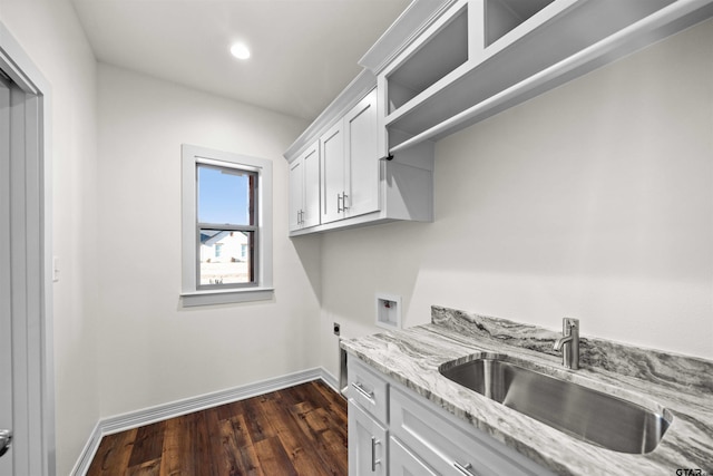 kitchen with light stone countertops, dark hardwood / wood-style floors, white cabinetry, and sink