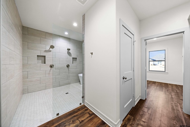 bathroom with tiled shower and hardwood / wood-style floors