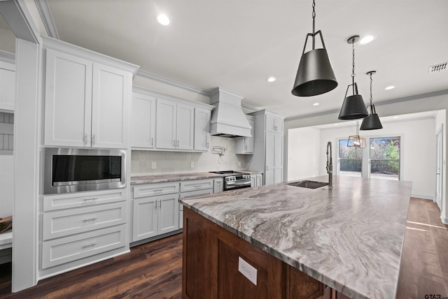 kitchen featuring white cabinets, appliances with stainless steel finishes, custom exhaust hood, and sink