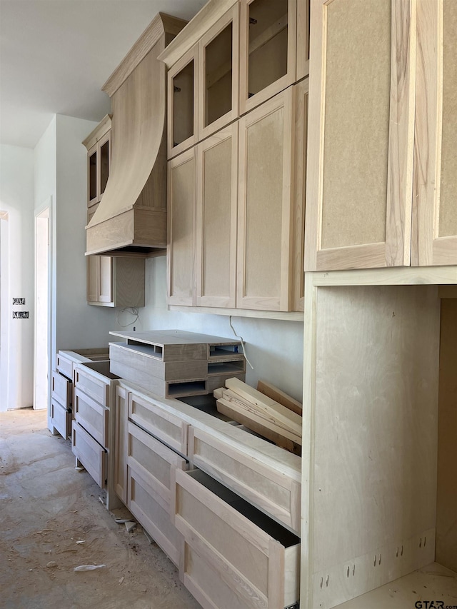 kitchen with light brown cabinets and custom range hood