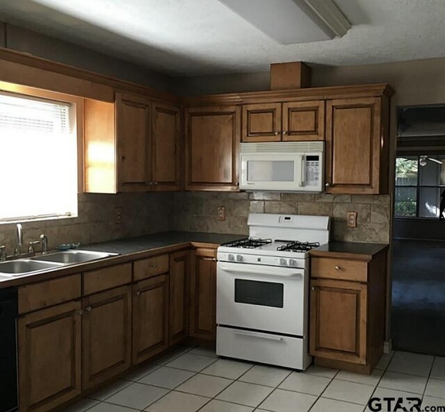 10414 Mist Ln, Houston, TX 77070 - kitchen featuring white appliances, a sink, dark countertops, and healthy amount of natural light