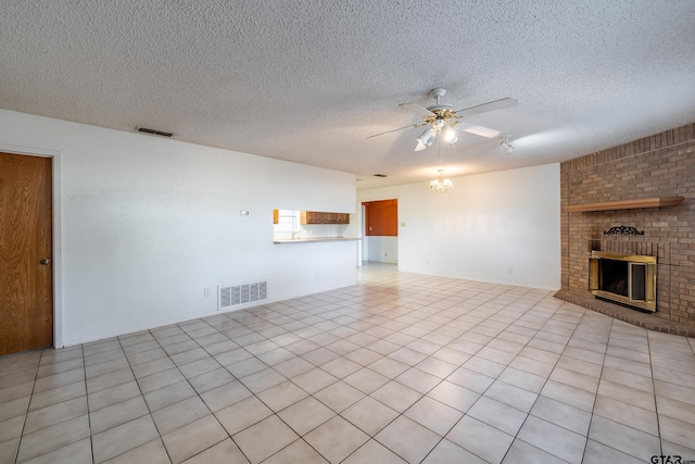 unfurnished living room featuring a brick fireplace, ceiling fan with notable chandelier, a textured ceiling, and light tile patterned floors