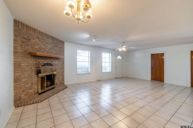 unfurnished living room featuring a textured ceiling, ceiling fan with notable chandelier, light tile patterned flooring, and a brick fireplace