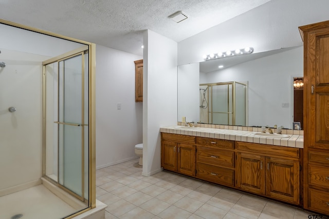 bathroom featuring tile patterned floors, vanity, a textured ceiling, and a shower with door