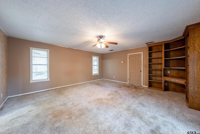 carpeted spare room with ceiling fan, a textured ceiling, and a healthy amount of sunlight