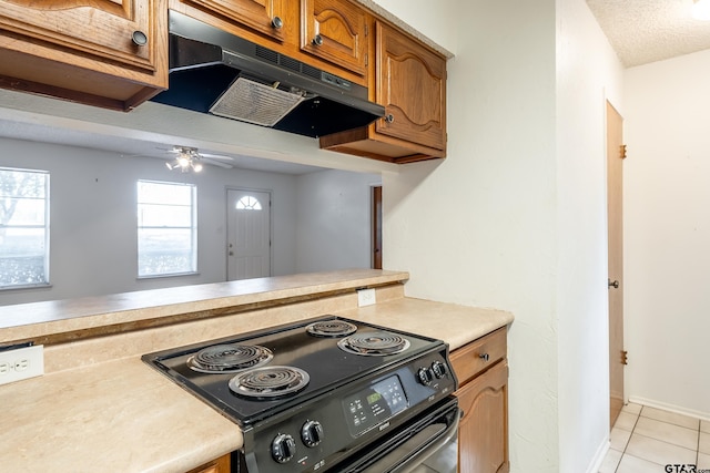 kitchen with a textured ceiling, black electric range oven, light tile patterned floors, kitchen peninsula, and ceiling fan