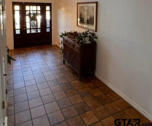 entryway featuring dark tile patterned floors and baseboards