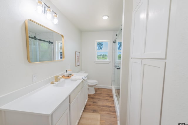 bathroom with toilet, vanity, an enclosed shower, and hardwood / wood-style floors