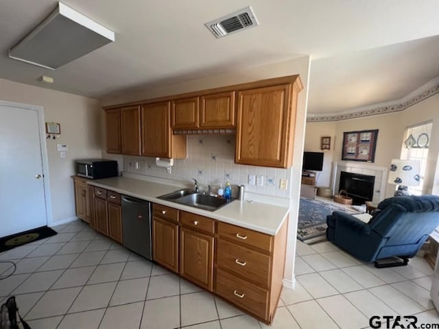 kitchen with visible vents, a sink, a fireplace, light countertops, and dishwashing machine