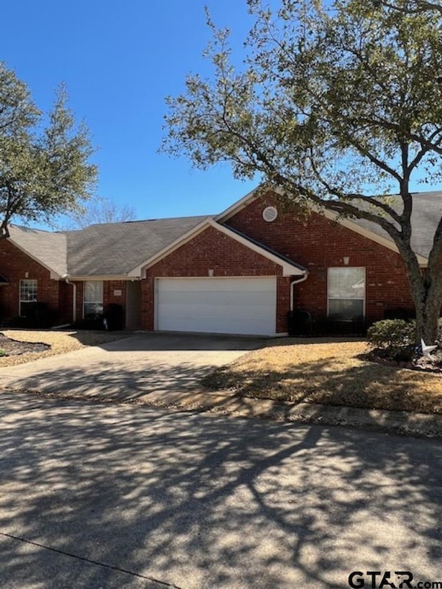 ranch-style home featuring brick siding, an attached garage, and driveway