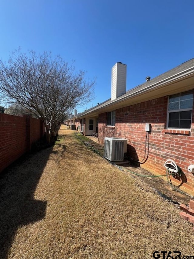 view of yard featuring central AC and fence