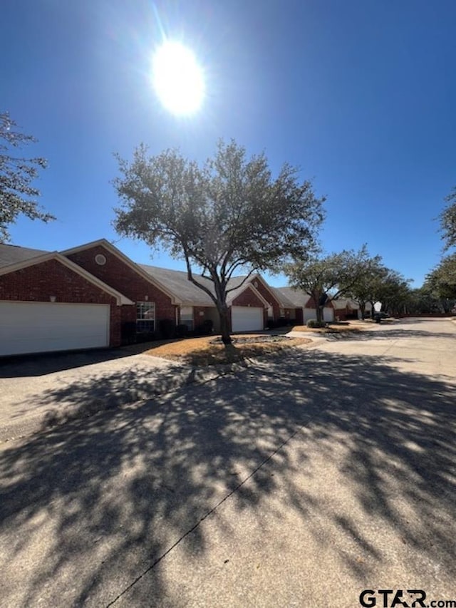 view of front of house with an attached garage, brick siding, and driveway