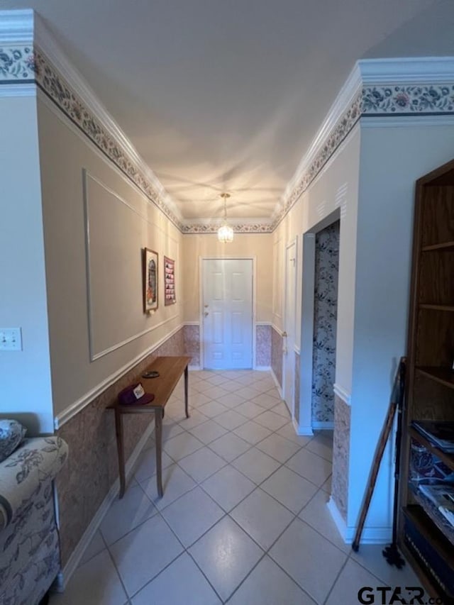 hall with light tile patterned floors, a notable chandelier, and ornamental molding