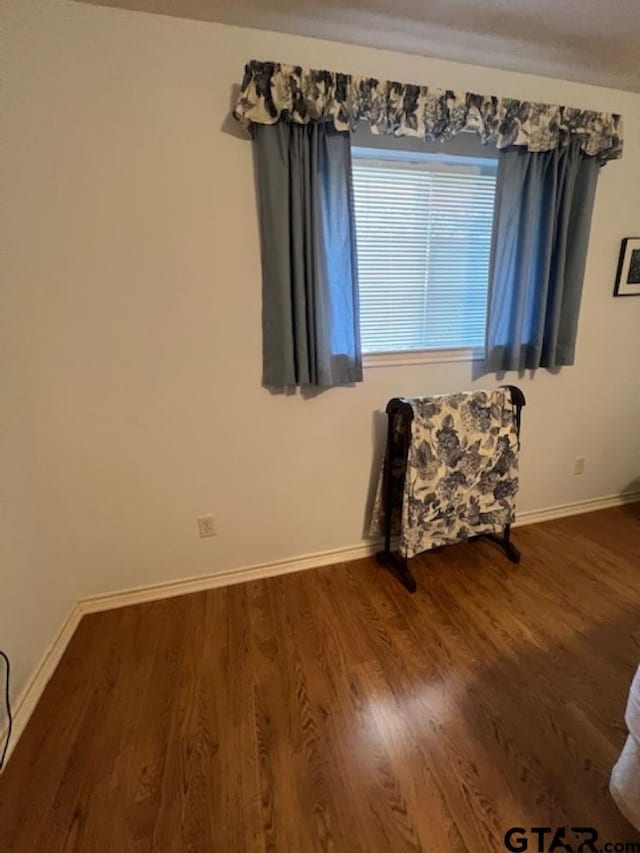 unfurnished room with baseboards and dark wood-style floors