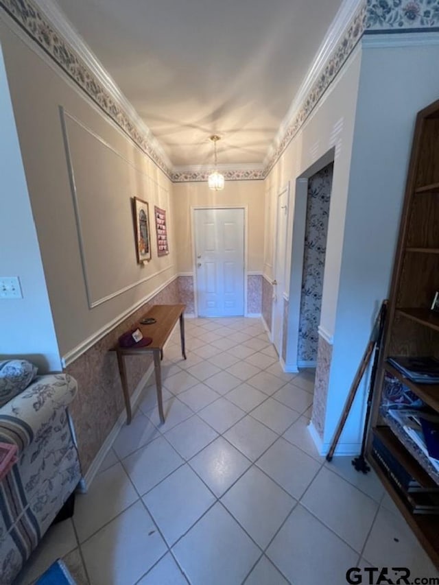 hallway with light tile patterned floors, a wainscoted wall, a chandelier, and ornamental molding